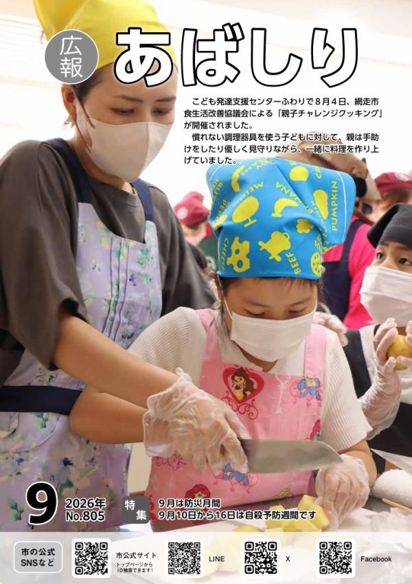 親子チャレンジクッキングで母親が子どもの持つ包丁に手を添えている写真が掲載された広報あばしりの表紙