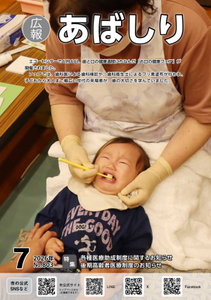 赤ちゃんが泣きながら歯科衛生士の膝の上で歯にフッ素を塗ってもらっている広報紙の表紙写真